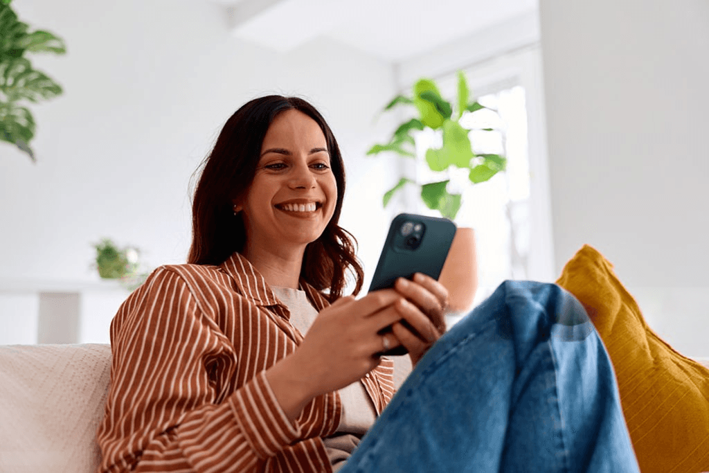 Mulher sorrindo usando o celular, simulando o Empréstimo Pessoal RC