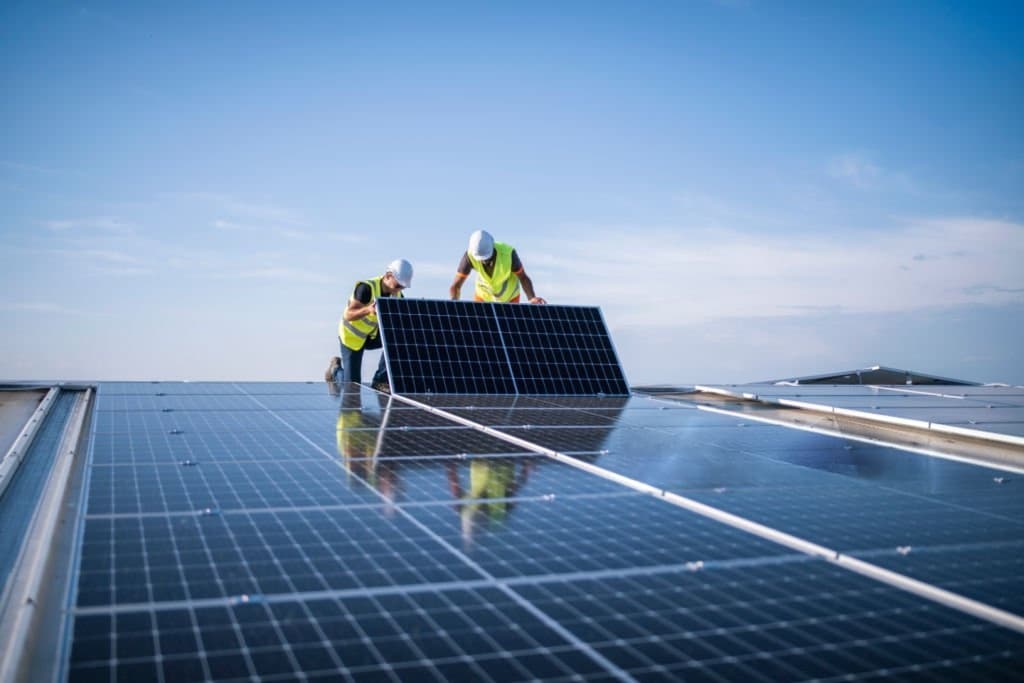Equipe técnica manuseando painel solar em usina compartilhada